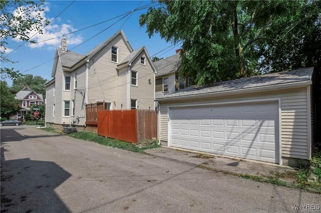 view of side of property featuring fence, a garage, and an outbuilding