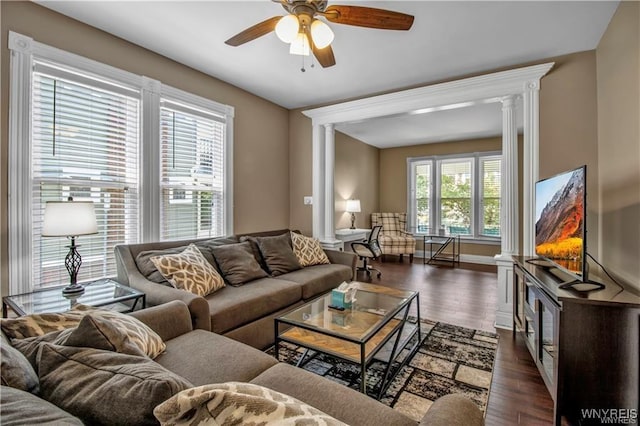 living area with decorative columns, ceiling fan, and dark wood-type flooring