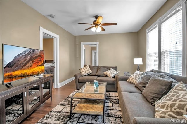 living room featuring a ceiling fan, dark wood-type flooring, and baseboards