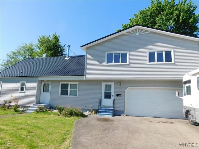 view of front of house featuring an attached garage, a front yard, driveway, and metal roof