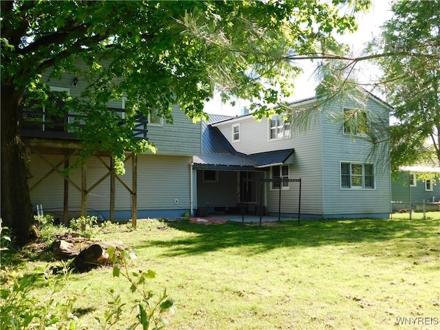 back of property featuring a yard and metal roof