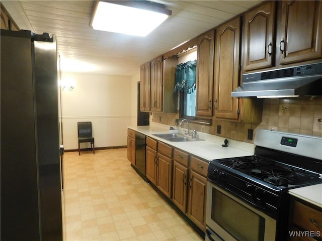 kitchen featuring gas stove, under cabinet range hood, a sink, dishwasher, and light countertops