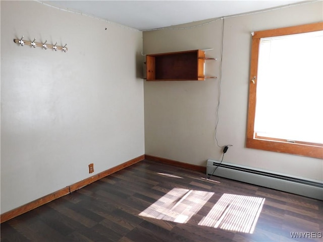 empty room with a baseboard radiator, plenty of natural light, baseboards, and dark wood-type flooring