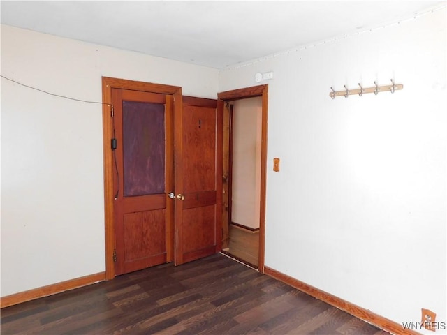 spare room with dark wood-type flooring and baseboards