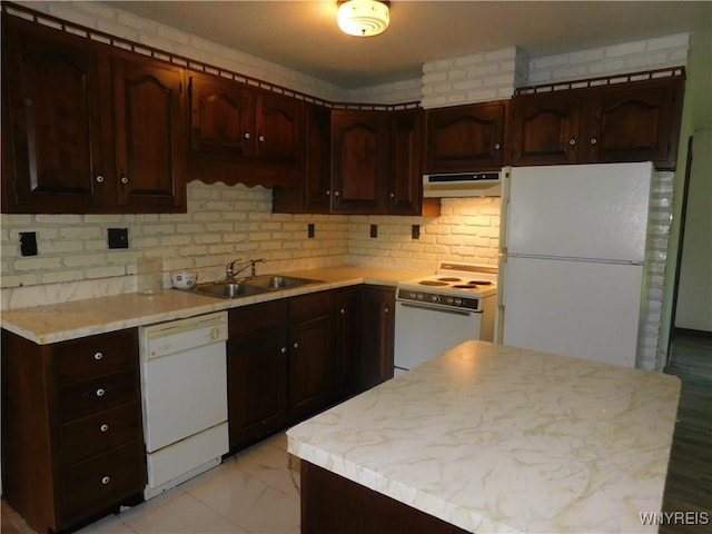 kitchen featuring white appliances, a sink, under cabinet range hood, light countertops, and dark brown cabinets