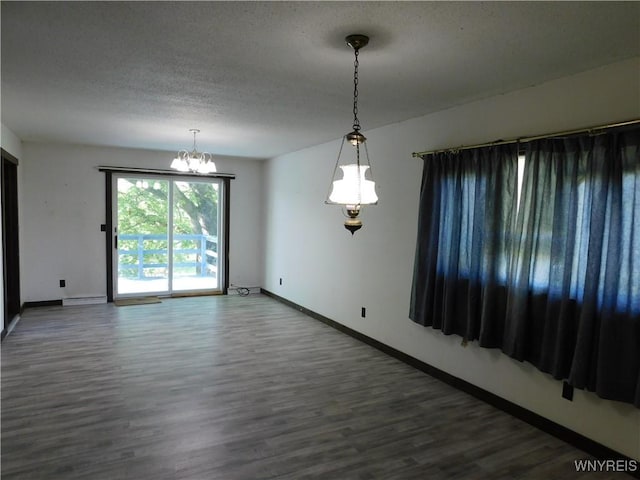 empty room featuring a chandelier, wood finished floors, baseboards, and a textured ceiling