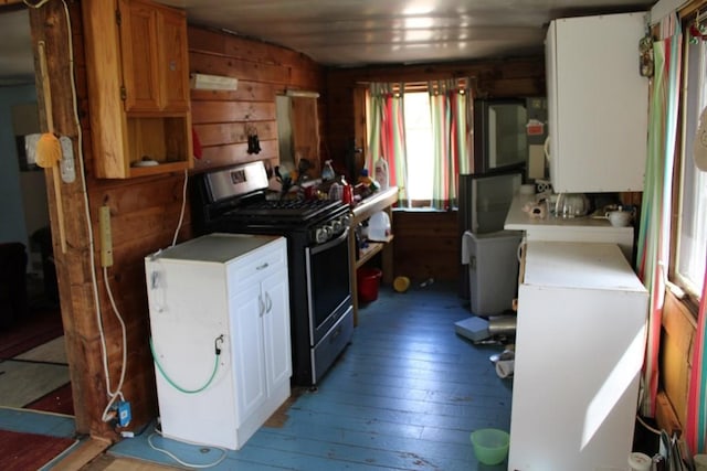 489 Ten Eyck Rd, Decatur, NY 12043 - kitchen with stainless steel gas stove, light wood-style floors, light countertops, and wood walls