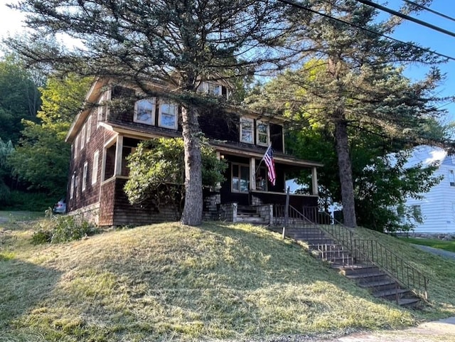 view of front of home featuring stairway, a porch, and a front yard