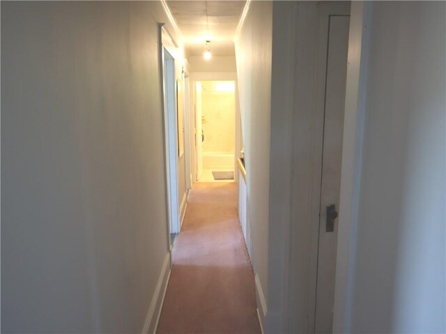 corridor with baseboards and light carpet