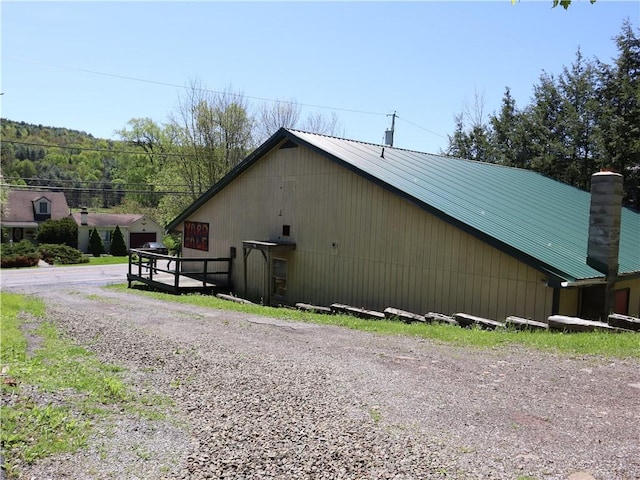 view of side of property with metal roof and a chimney