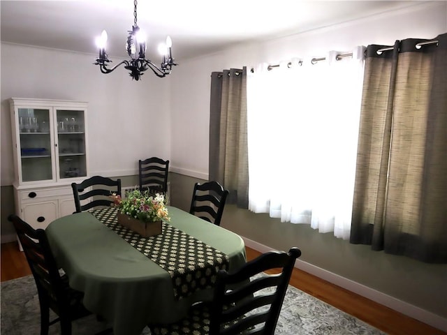 dining space featuring a chandelier, wood finished floors, and baseboards