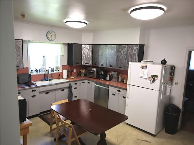 kitchen featuring freestanding refrigerator, dishwasher, a sink, and white cabinets