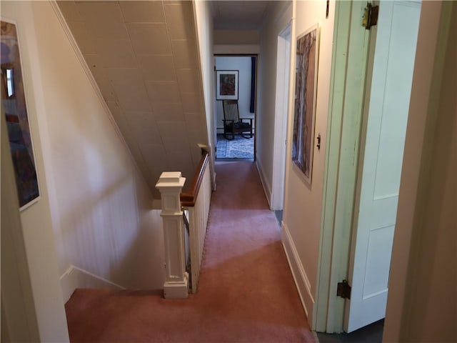 hallway featuring carpet, an upstairs landing, and baseboards