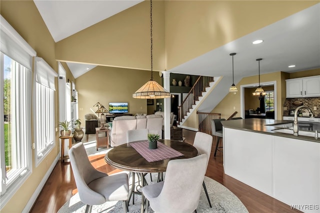 dining room with stairs, plenty of natural light, dark wood finished floors, recessed lighting, and high vaulted ceiling
