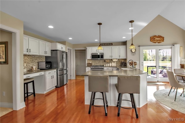 kitchen featuring appliances with stainless steel finishes, a peninsula, a kitchen breakfast bar, a sink, and recessed lighting