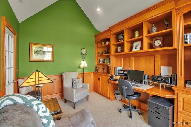 office space featuring built in desk, light colored carpet, a wainscoted wall, and high vaulted ceiling