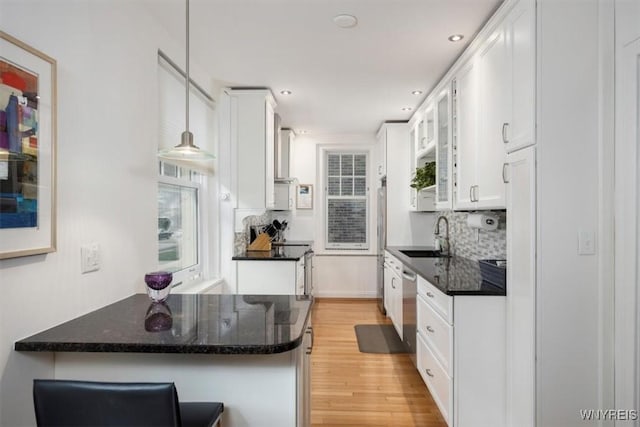 kitchen featuring a sink, white cabinetry, backsplash, light wood-style flooring, and recessed lighting