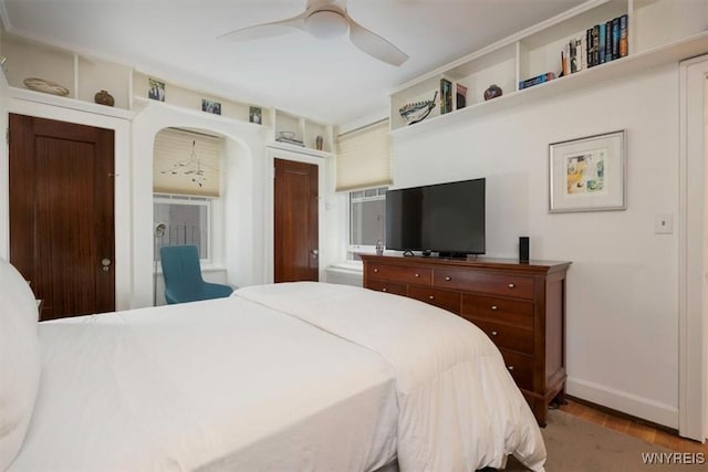 bedroom featuring baseboards, wood finished floors, and ceiling fan