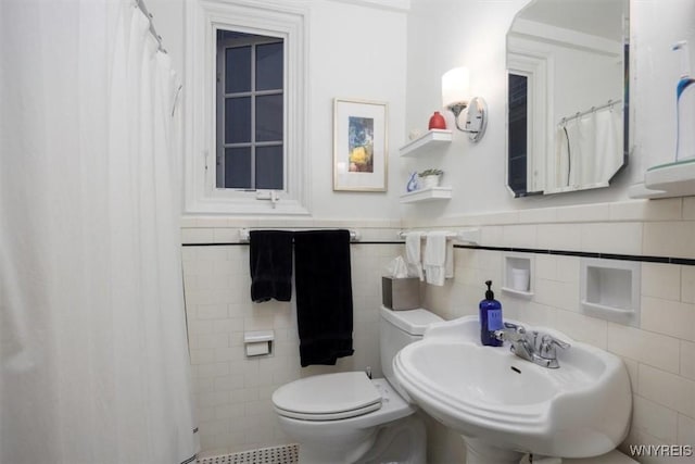 full bath featuring tile walls, a sink, toilet, a wainscoted wall, and a shower with shower curtain