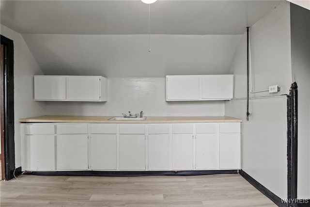 75 Box Ave, Buffalo, NY 14211 - kitchen featuring a sink, white cabinets, vaulted ceiling, light countertops, and light wood-type flooring