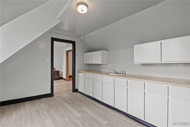 75 Box Ave, Buffalo, NY 14211 - kitchen featuring a sink, lofted ceiling, light countertops, light wood-type flooring, and white cabinets