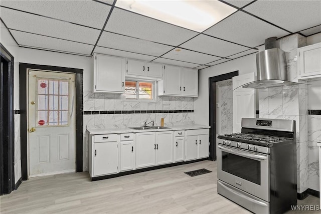 75 Box Ave, Buffalo, NY 14211 - kitchen with stainless steel gas stove, wall chimney exhaust hood, light countertops, white cabinets, and backsplash