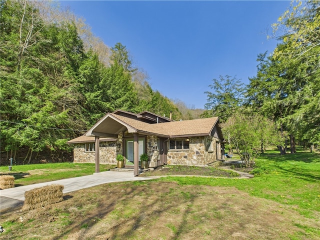 view of front of property with stone siding, a front yard, driveway, and a porch