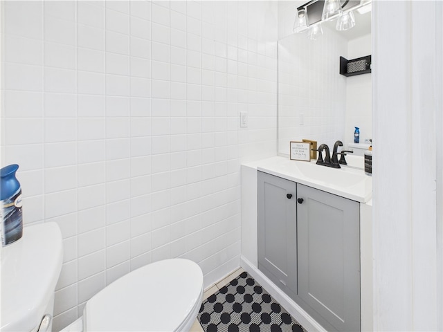 bathroom featuring toilet, tile walls, vanity, and tile patterned flooring