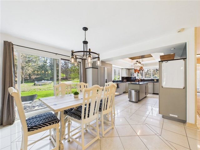 dining space with a chandelier, plenty of natural light, light tile patterned floors, and a tray ceiling