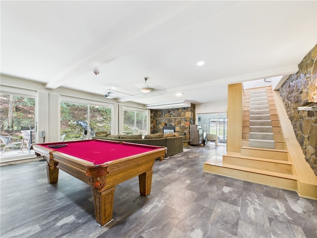 recreation room with a stone fireplace, plenty of natural light, billiards, beam ceiling, and ceiling fan