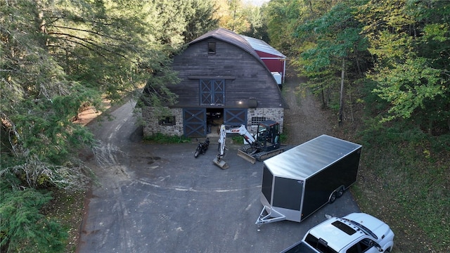 view of property's community featuring a barn, a forest view, and an outbuilding