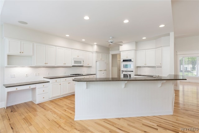 56 Sunset Ln, Orchard Park, NY 14127 - kitchen featuring white appliances, light wood-type flooring, ceiling fan, backsplash, and a kitchen breakfast bar