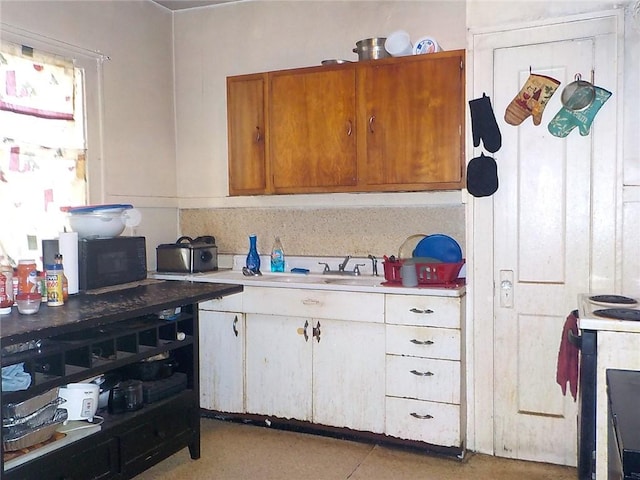 kitchen featuring black microwave, white electric range oven, a sink, light countertops, and brown cabinetry