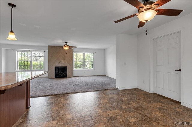 1275 Center St, Aurora, NY 14052 - unfurnished living room featuring a ceiling fan, a fireplace, baseboards, and dark stone finish flooring