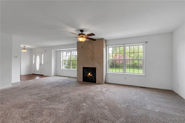 1275 Center St, Aurora, NY 14052 - unfurnished living room with carpet, a ceiling fan, a large fireplace, and baseboards