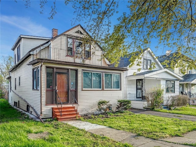 view of front of property with entry steps, a front yard, and a chimney