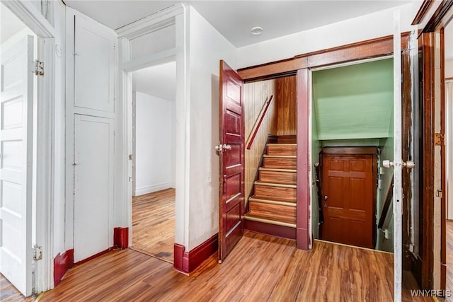 corridor with wood finished floors, stairway, and baseboards
