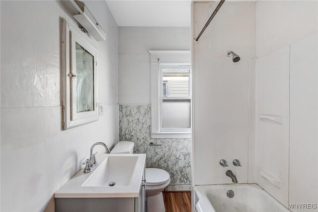 full bath featuring toilet, wood finished floors, vanity,  shower combination, and a wall mounted air conditioner