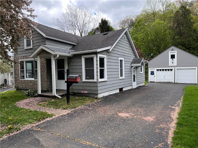332 Jamestown St, Persia, NY 14070 - view of front facade with an outbuilding, a shingled roof, a detached garage, a chimney, and stone siding
