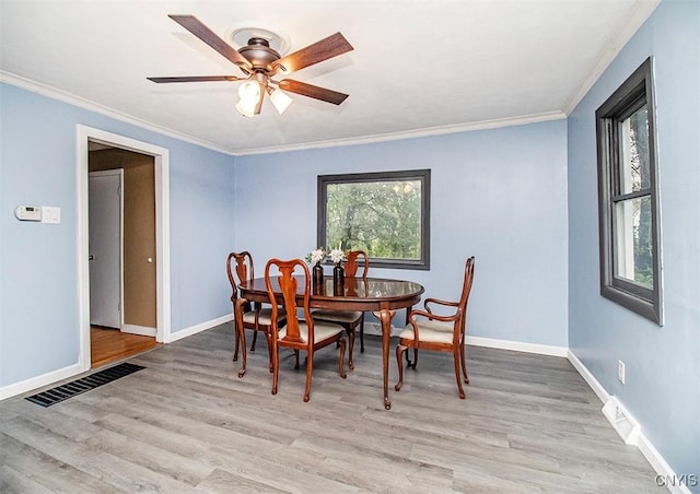 dining room featuring crown molding, light wood-style flooring, baseboards, and ceiling fan