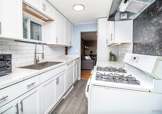 kitchen with white appliances, a sink, exhaust hood, white cabinetry, and wood finished floors