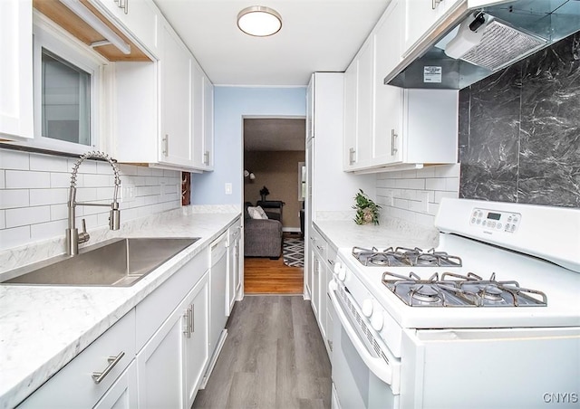 kitchen with white appliances, under cabinet range hood, a sink, and decorative backsplash