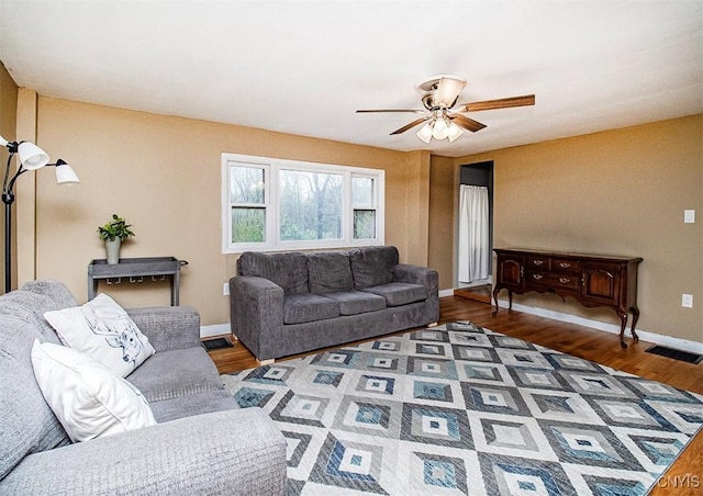 living area featuring a ceiling fan, baseboards, and wood finished floors