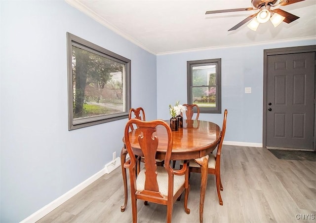 dining room with light wood-type flooring, baseboards, crown molding, and a ceiling fan