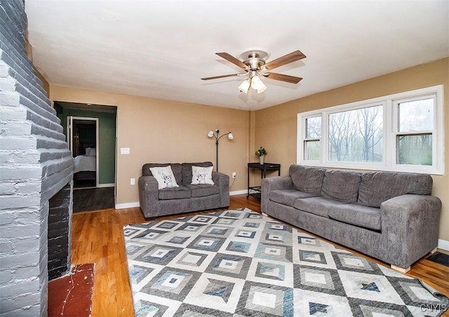 living area featuring wood finished floors, a ceiling fan, and baseboards