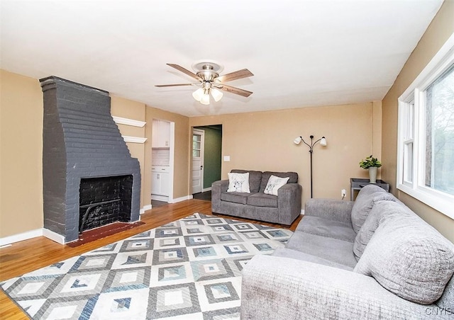 living room featuring ceiling fan, wood finished floors, a fireplace, and baseboards