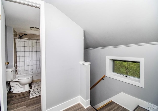 stairs featuring wood finished floors, baseboards, and lofted ceiling
