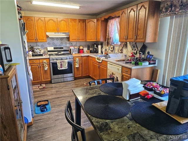 6943 Academy Ln, Lockport-Town, NY 14094 - kitchen featuring stainless steel appliances, under cabinet range hood, wood finished floors, brown cabinets, and tasteful backsplash