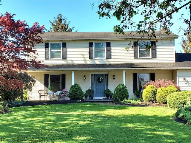view of front of property featuring covered porch, a front lawn, and brick siding