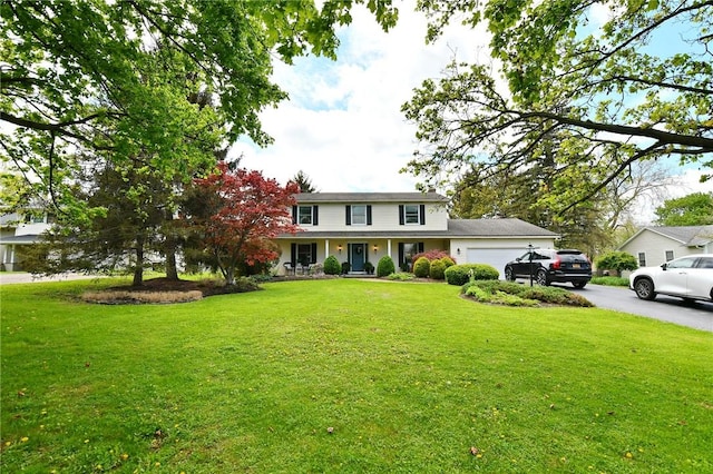 view of front of house with a garage, a front yard, a porch, and driveway